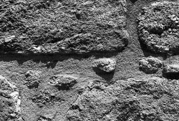 Stone wall with grey textured surface. Old weathered rock pattern with rough masonry blocks, cracked