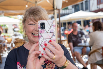 dame s'amusant avec son téléphone portable en terrasse l'été en faisant un selfie