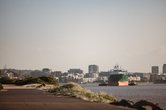 Cargo ship escorted by tug boats leaving the Newcastle Port on the Hunter River