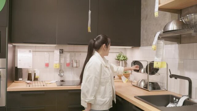 Individual with shopping basket exploring model kitchen setup with another shopper, highlighting modern lifestyle, interior design, household products, retail showroom experience and home improvement
