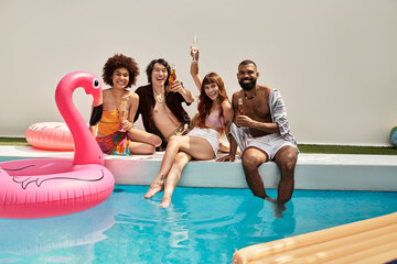 Stylish friends celebrate summer joyfully at a vibrant pool party with laughter and drinks