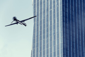 A kamikaze drone flies near a glass skyscraper, the propeller is in motion.