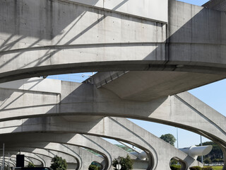 Fototapeta premium Modern concrete bridge structure with curved arches and shadows. Urban infrastructure perspective