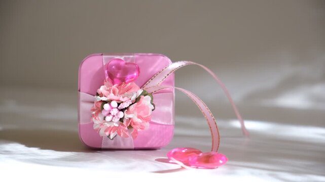 Pink gift box with flowers, crystal heart, sunlight. Minimalistic composition enhances the focus on the great moment. Wedding, Birthday, Valentines Day. Template greeting card. Happy celebration