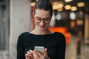 Fototapeta premium Portrait of young businesswoman reading email on smartphone.