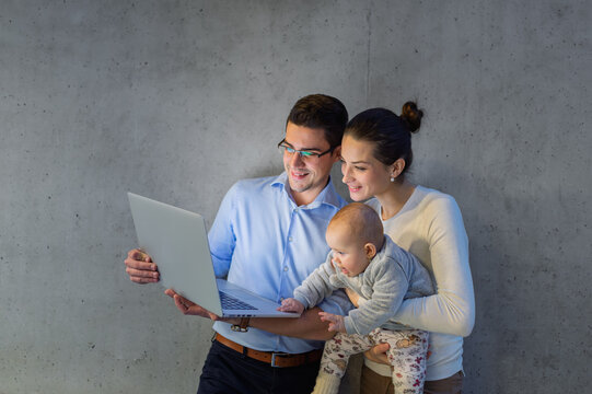 Mother with baby sitting next to working businessman father.