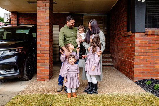Happy family standing entry way of their house