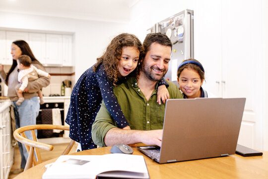 Father and daughters using laptop on dining table