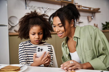 Bonding moments between mother and daughter at home over shared device