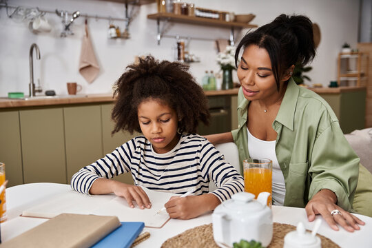 Joyful moments of learning at home between mother and daughter in a cozy kitchen
