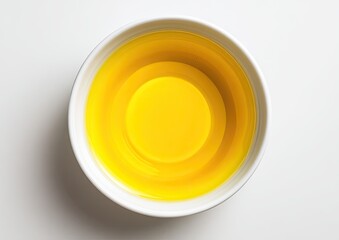 Top-down view of a small, white bowl filled with yellow liquid.  The liquid has a slight concentric pattern