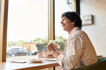 Joyful moment of a handsome young man enjoying coffee at a cafe in a vibrant atmosphere