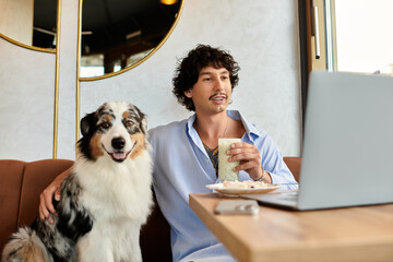 Charming young man enjoys coffee with his dog while working on a laptop at a cozy cafe