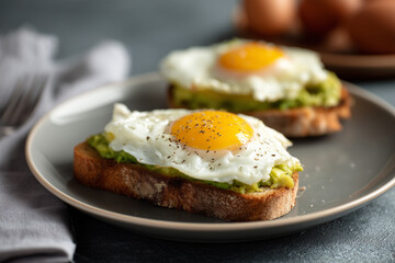 Delicious avocado toast topped with eggs on breakfast plate