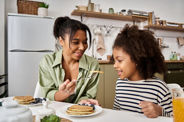 Mother and daughter sharing a joyful breakfast moment at home with pancakes