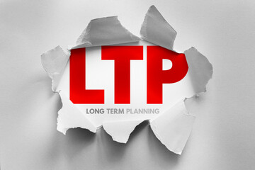 LTP (Long Term Planning) abbreviation concept revealed through torn paper. Strategic foresight,...
