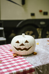 White jack-o'-lantern on picnic table near RV at campsite with copy space, camping during halloween concept