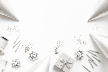 Festive party decoration in silver color with gift box and carnaval caps on white background, top view