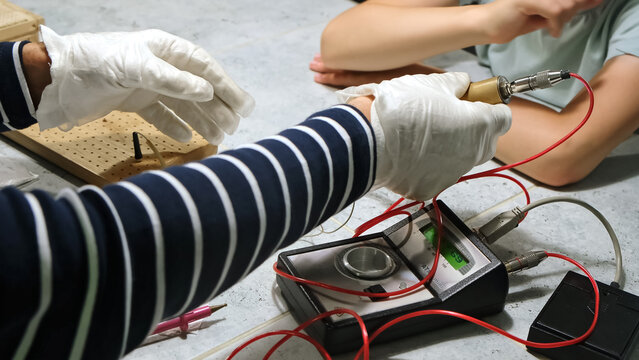 Homeopathic doctor gives a brass handpiece to patient to electropuncture diagnostics using Foll method by pressing on hand's points to determine bioenergetics. Selection of homeopathic remedies