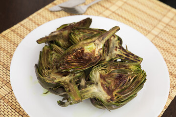 cooked fried halves artichokes on white plate