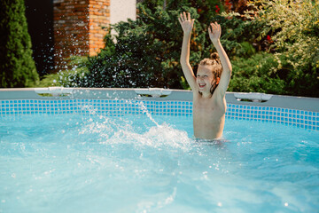 A young boy enjoys a sunny day as he splashes around in a backyard pool. He raises his hands in excitement, interacting with his family and enjoying the water.