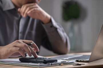 businessman calculating with calculator and working on laptop, representing accounting, tax...