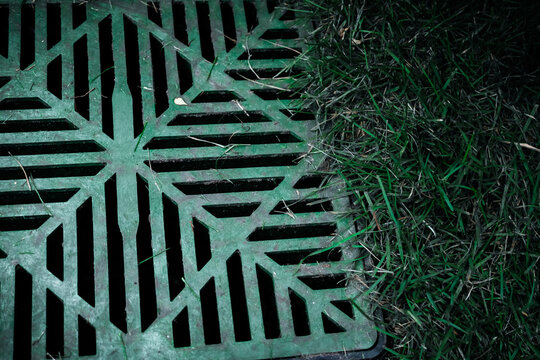 a storm drain installed next to grass, also known as a catch basin or yard drain, which is a common component of a drainage system