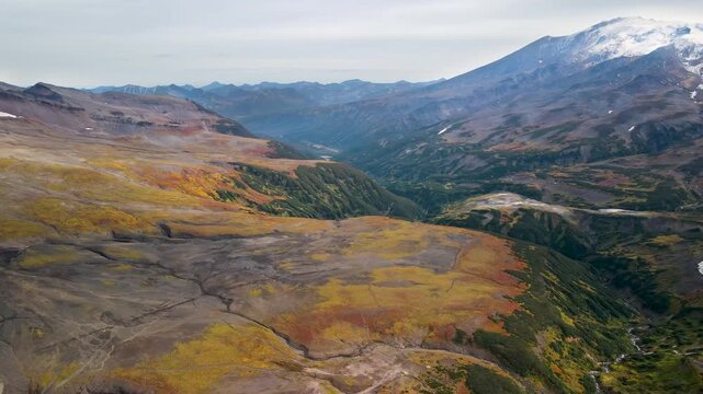 View of Mutnovsky Volcano (2,322 m) on the Kamchatka. Its peak is covered with snow, while the colorful lower slopes remain in autumn hues. Mutnovsky is one of the most active volcanoes in Kamchatka.