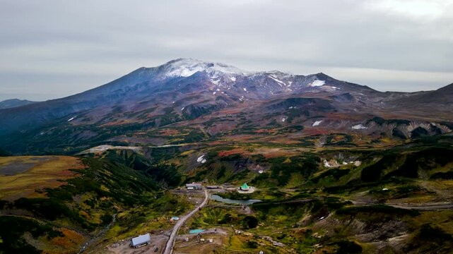 View of Mutnovsky Volcano (2,322 m) on the Kamchatka. Its peak is covered with snow, while the colorful lower slopes remain in autumn hues. Mutnovsky is one of the most active volcanoes in Kamchatka.
