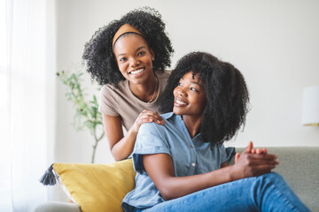 A affectionate mother and daughter sitting on sofa at home