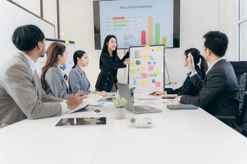 Group of business people discussing charts and graphs showing successful teamwork. Asian business team brainstorming meeting in office.