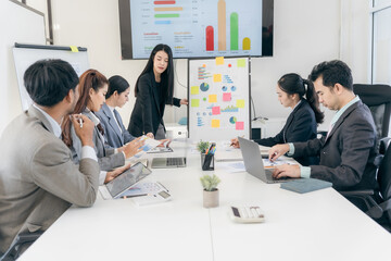 Group of business people discussing charts and graphs showing successful teamwork. Asian business team brainstorming meeting in office.