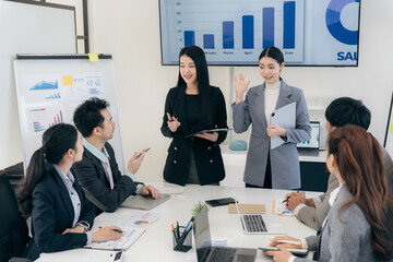 Group of business people discussing charts and graphs showing successful teamwork. Asian business team brainstorming meeting in office.