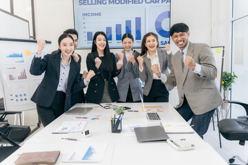 Group of happy Asian businesspeople congratulating each other to celebrate success in office conference room during meeting.