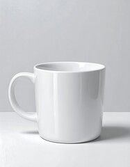 Obraz premium A clean, glossy white mug sits on a plain white surface, showcasing its simple design and smooth finish.