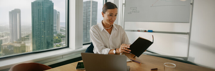 A businesswoman is diligently reviewing important documents within a modern office environment