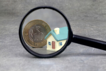 Model house and rupee coin through magnifying glass-Concept of savings and money growth 