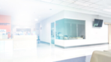Blur abstract background of corridor in clean hospital. Blurry view of aisle in office with light floor. Defocus walkway in white light building hall with patient registration at reception desk.