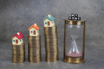 Stack of coins and model houses against grey background