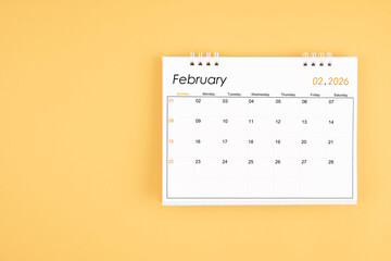 February 2026 desk calendar on yellow color background, position with copy space.