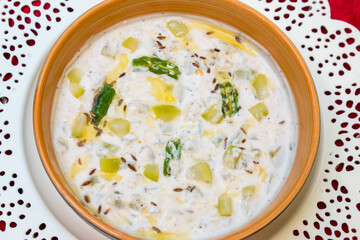 Bowl having curd or raita topped with cumin chili dadka. indian side dish for dinner or lunch. 