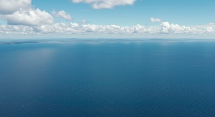 Fototapeta premium Serene ocean view beneath a partly cloudy sky offering a peaceful seascape vista filled with blue