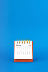 February 2026 white desk calendar on blue color background.