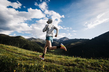 Trail runner running on the high altitude grassland mountain top trail