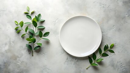 Elegant empty white plate with fresh green leaves on a textured gray background; minimalist flat lay, clean and serene aesthetic, perfect for food, restaurant, or health-related branding.