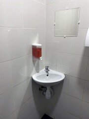 Corner sink on tile wall in toilet