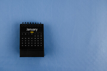 January 2026 black desk calendar on navy blue color leather background.