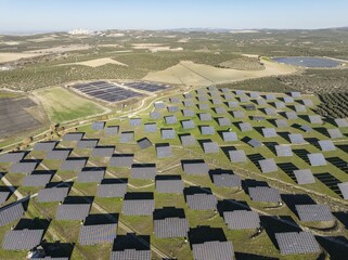 Rows of solar panels at a photovoltaic plant and the town of Espejo in the distance. Aerial view. Drone shot. Córdoba province, Andalucía, Spain