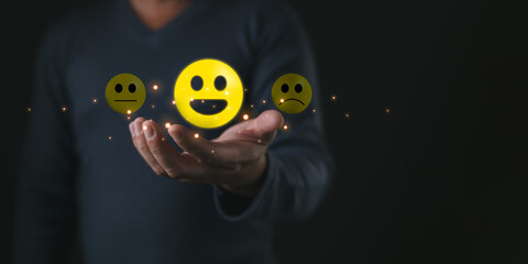 A person holds glowing emoticons showing happy,neutral,and sad faces symbolizing think positive...