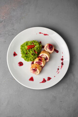 Elegant chicken roll with cranberry sauce on a white plate.